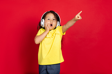 Image showing Beautiful emotional little girl isolated on red background. Half-lenght portrait of happy child gesturing