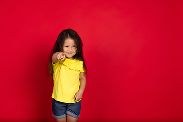 Image showing Beautiful emotional little girl isolated on red background. Half-lenght portrait of happy child gesturing