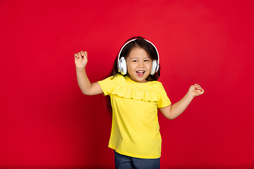 Image showing Beautiful emotional little girl isolated on red background. Half-lenght portrait of happy child gesturing