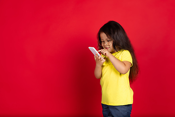 Image showing Beautiful emotional little girl isolated on red background. Half-lenght portrait of happy child gesturing