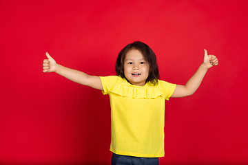 Image showing Beautiful emotional little girl isolated on red background. Half-lenght portrait of happy child gesturing