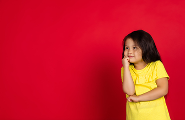 Image showing Beautiful emotional little girl isolated on red background. Half-lenght portrait of happy child gesturing