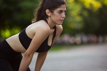 Image showing Young female athlete training in the city street in summer sunshine. Beautiful woman practicing, working out. Concept of sport, healthy lifestyle, movement, activity.