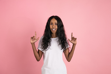 Image showing Cheerful african-american young woman isolated on pink background, emotional and expressive