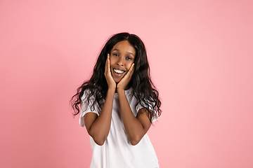 Image showing Cheerful african-american young woman isolated on pink background, emotional and expressive