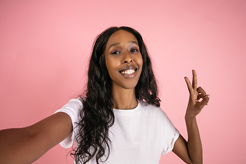 Image showing Cheerful african-american young woman isolated on pink background, emotional and expressive