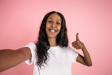 Image showing Cheerful african-american young woman isolated on pink background, emotional and expressive