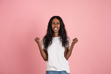 Image showing Cheerful african-american young woman isolated on pink background, emotional and expressive