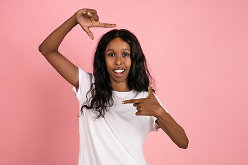 Image showing Cheerful african-american young woman isolated on pink background, emotional and expressive