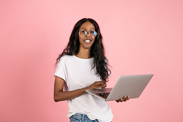 Image showing Cheerful african-american young woman isolated on pink background, emotional and expressive