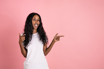 Image showing Cheerful african-american young woman isolated on pink background, emotional and expressive