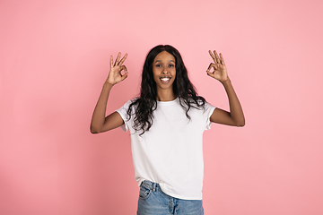 Image showing Cheerful african-american young woman isolated on pink background, emotional and expressive