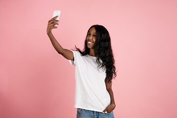 Image showing Cheerful african-american young woman isolated on pink background, emotional and expressive