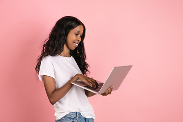 Image showing Cheerful african-american young woman isolated on pink background, emotional and expressive