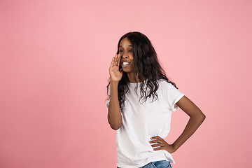 Image showing Cheerful african-american young woman isolated on pink background, emotional and expressive