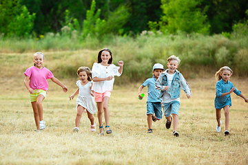 Image showing Kids, children running on meadow in summer\'s sunlight