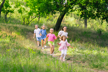 Image showing Kids, children running on meadow in summer\'s sunlight