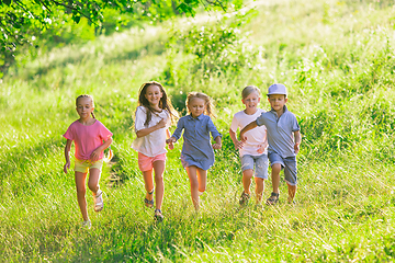 Image showing Kids, children running on meadow in summer\'s sunlight