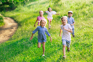 Image showing Kids, children running on meadow in summer\'s sunlight