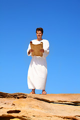 Image showing man reading scroll in rocky desert land scape