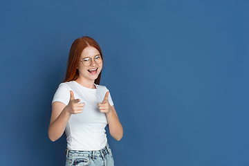 Image showing Caucasian young girl\'s portrait isolated on blue studio background. Beautiful female model. Concept of human emotions, facial expression, sales, ad, youth culture.