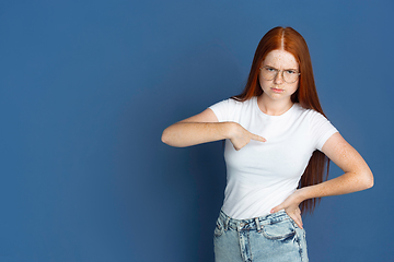 Image showing Caucasian young girl\'s portrait isolated on blue studio background. Beautiful female model. Concept of human emotions, facial expression, sales, ad, youth culture.