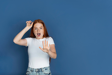 Image showing Caucasian young girl\'s portrait isolated on blue studio background. Beautiful female model. Concept of human emotions, facial expression, sales, ad, youth culture.