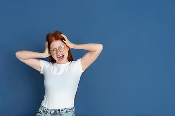 Image showing Caucasian young girl\'s portrait isolated on blue studio background. Beautiful female model. Concept of human emotions, facial expression, sales, ad, youth culture.