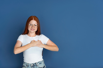 Image showing Caucasian young girl\'s portrait isolated on blue studio background. Beautiful female model. Concept of human emotions, facial expression, sales, ad, youth culture.