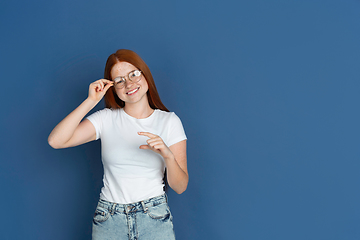 Image showing Caucasian young girl\'s portrait isolated on blue studio background. Beautiful female model. Concept of human emotions, facial expression, sales, ad, youth culture.