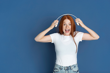 Image showing Caucasian young girl\'s portrait isolated on blue studio background. Beautiful female model. Concept of human emotions, facial expression, sales, ad, youth culture.