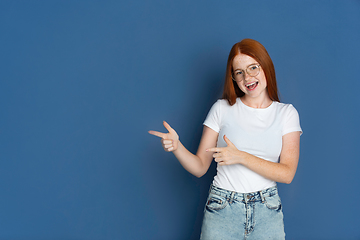 Image showing Caucasian young girl\'s portrait isolated on blue studio background. Beautiful female model. Concept of human emotions, facial expression, sales, ad, youth culture.