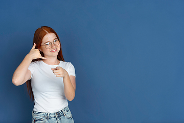 Image showing Caucasian young girl\'s portrait isolated on blue studio background. Beautiful female model. Concept of human emotions, facial expression, sales, ad, youth culture.