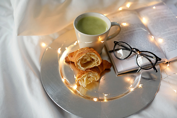 Image showing croissants, matcha tea, book and glasses in bed