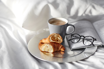 Image showing croissants, cup of coffee and book in bed at home