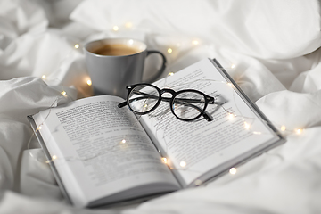 Image showing cup of coffee, book, glasses and garland in bed