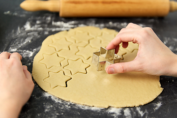 Image showing hands cutting dough with star mold on table