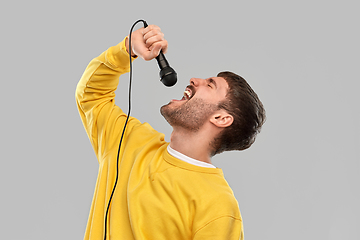 Image showing man in yellow sweatshirt with microphone singing