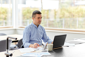 Image showing man in earphones with laptop working at home