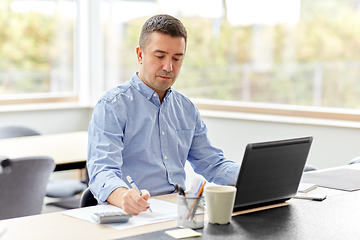 Image showing man with calculator and papers working at home