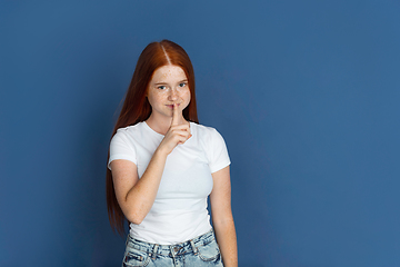 Image showing Caucasian young girl\'s portrait isolated on blue studio background. Beautiful female model. Concept of human emotions, facial expression, sales, ad, youth culture.