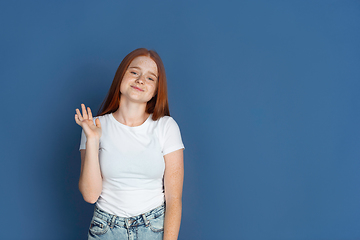 Image showing Caucasian young girl\'s portrait isolated on blue studio background. Beautiful female model. Concept of human emotions, facial expression, sales, ad, youth culture.