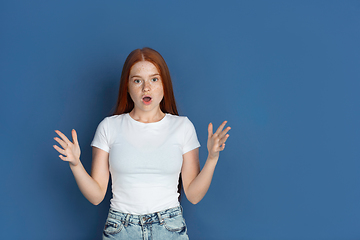 Image showing Caucasian young girl\'s portrait isolated on blue studio background. Beautiful female model. Concept of human emotions, facial expression, sales, ad, youth culture.