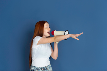 Image showing Caucasian young girl\'s portrait isolated on blue studio background. Beautiful female model. Concept of human emotions, facial expression, sales, ad, youth culture.