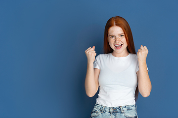 Image showing Caucasian young girl\'s portrait isolated on blue studio background. Beautiful female model. Concept of human emotions, facial expression, sales, ad, youth culture.