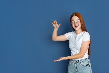 Image showing Caucasian young girl\'s portrait isolated on blue studio background. Beautiful female model. Concept of human emotions, facial expression, sales, ad, youth culture.