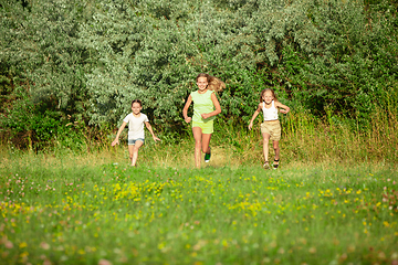 Image showing Kids, children running on meadow in summer\'s sunlight