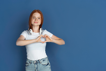 Image showing Caucasian young girl\'s portrait isolated on blue studio background. Beautiful female model. Concept of human emotions, facial expression, sales, ad, youth culture.