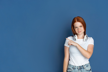 Image showing Caucasian young girl\'s portrait isolated on blue studio background. Beautiful female model. Concept of human emotions, facial expression, sales, ad, youth culture.