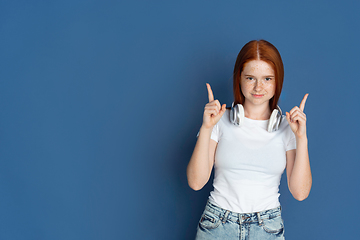 Image showing Caucasian young girl\'s portrait isolated on blue studio background. Beautiful female model. Concept of human emotions, facial expression, sales, ad, youth culture.